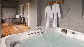 A spa area with a hot tub, wooden flooring, and white bathrobes hanging on the wall. - Le Durkestrete Cellar (Haverfordwest)