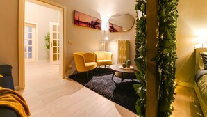A modern living room with a sofa, two yellow armchairs, a round coffee table, and a mirror on the wall.