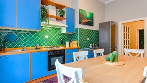 A modern kitchen with blue cabinets, a wooden dining table, and a cactus centerpiece.