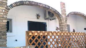 Un bâtiment aux murs en pierre, une clôture en treillis de bois et une porte avec un volet noir.