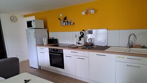 A modern kitchen with white cabinets, a microwave, a coffee maker, and a sink. - Appartement Refait à Neuf Tout Équipé en RDC Avec Jardin Terrasse ,barbecue (Avrillé)