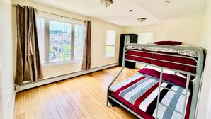 Una habitación con literas, una ventana con cortinas, un radiador y un armario.