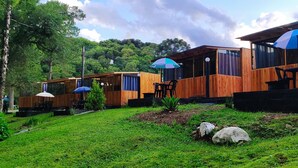 A wooden cabin-style building with outdoor seating areas and umbrellas. - Cabanas Loft Paraíso (Gramado)