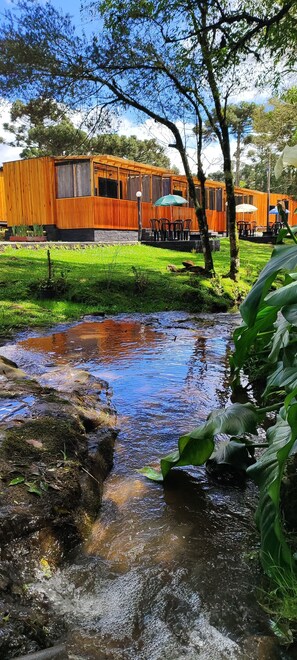 A wooden building with outdoor seating and a small stream.
