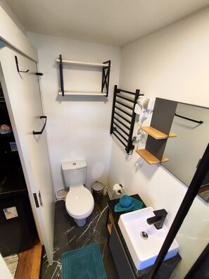 Une petite salle de bain comprenant des toilettes, un lavabo et un porte-serviettes.