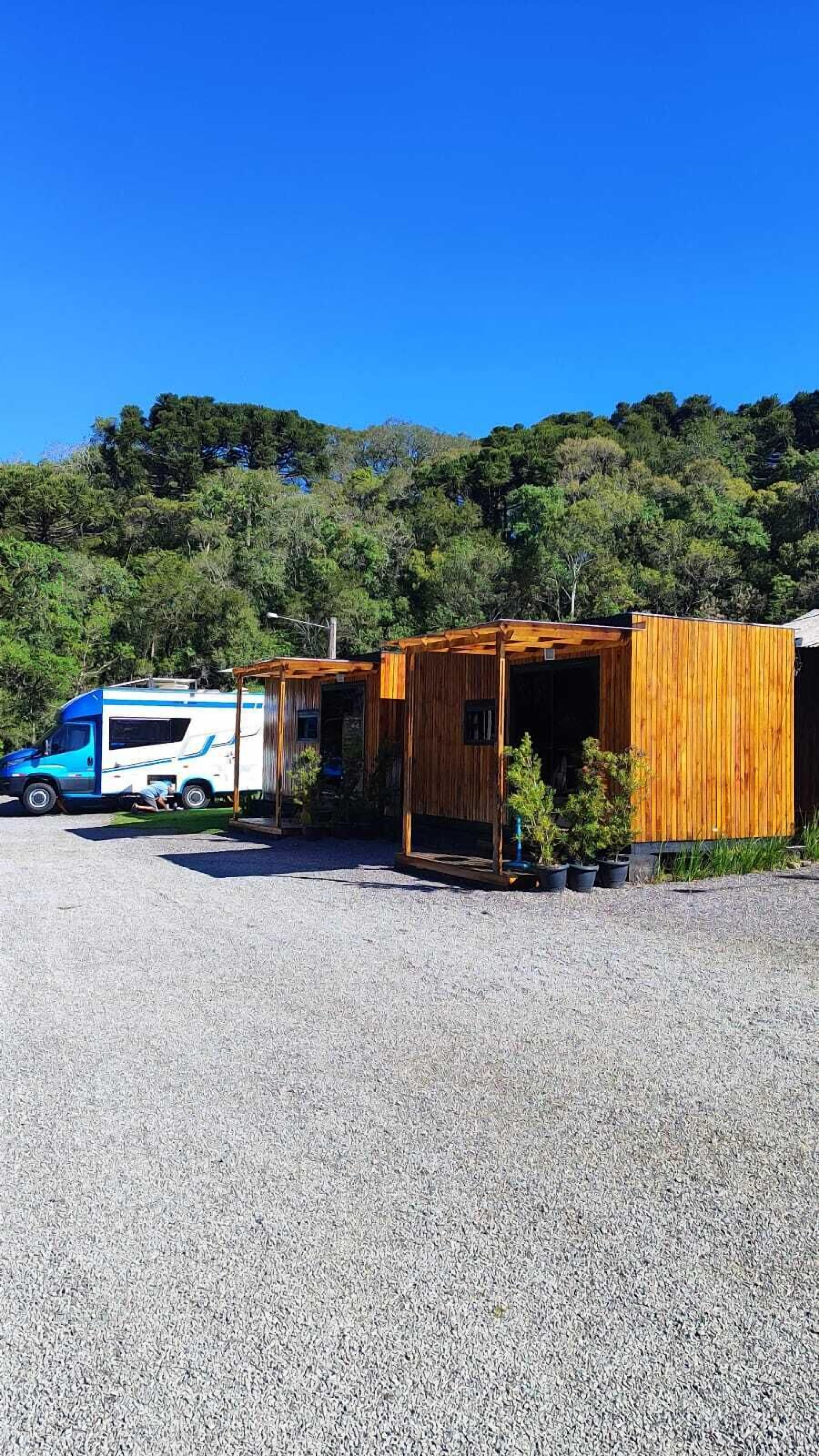 Una caravana estacionada en un área de grava con estructuras de madera cerca.