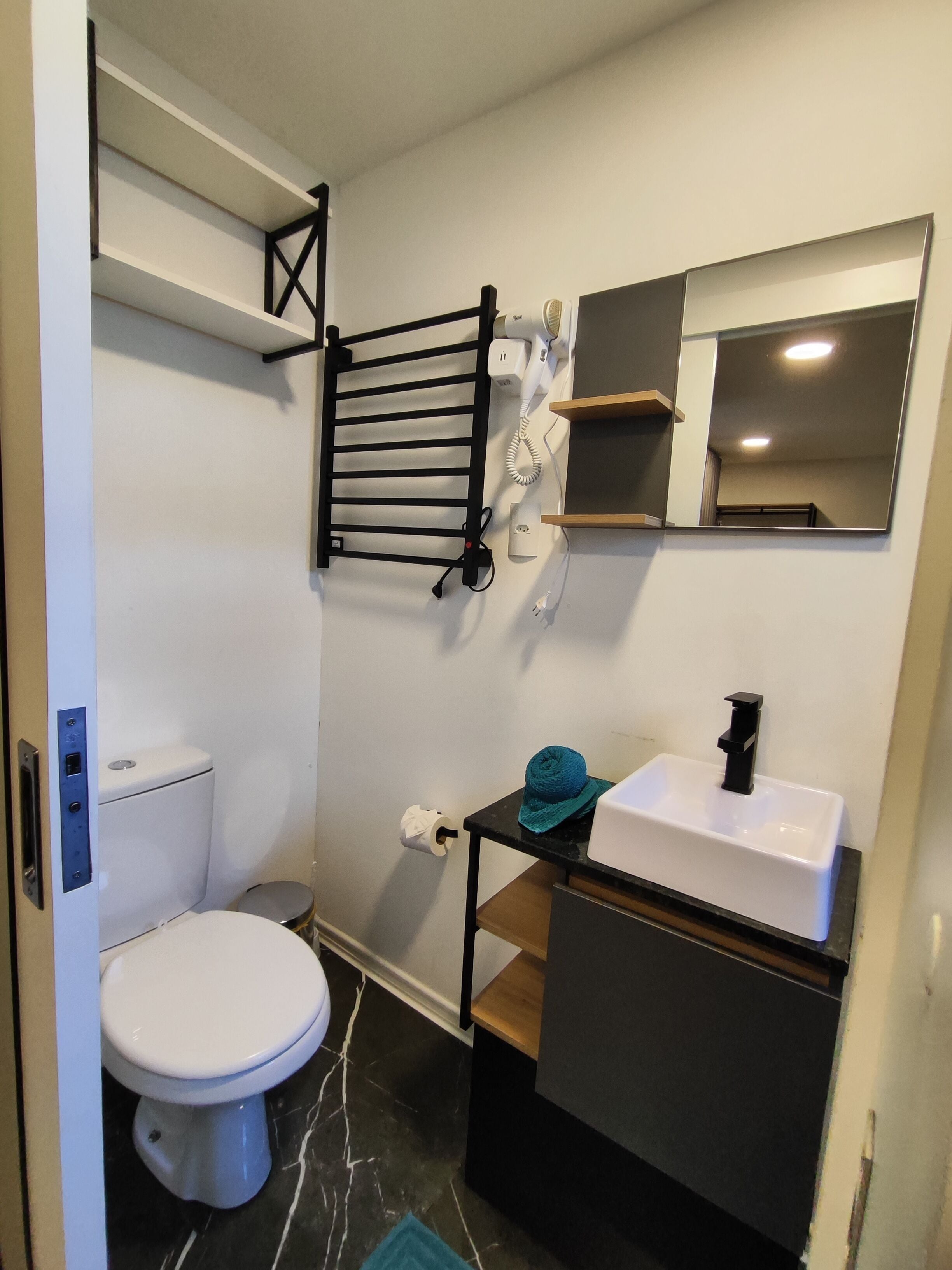 Un bagno compatto con il water, un lavandino, un portaserviti, uno specchio e una doccia.