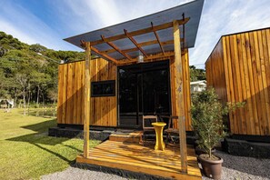 Une cabane en bois avec un porche couvert, une petite table et des plantes en pot.