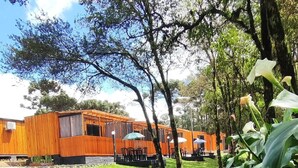 A wooden building with a patio area and a stream. - Cabanas Loft Paraíso (Gramado)