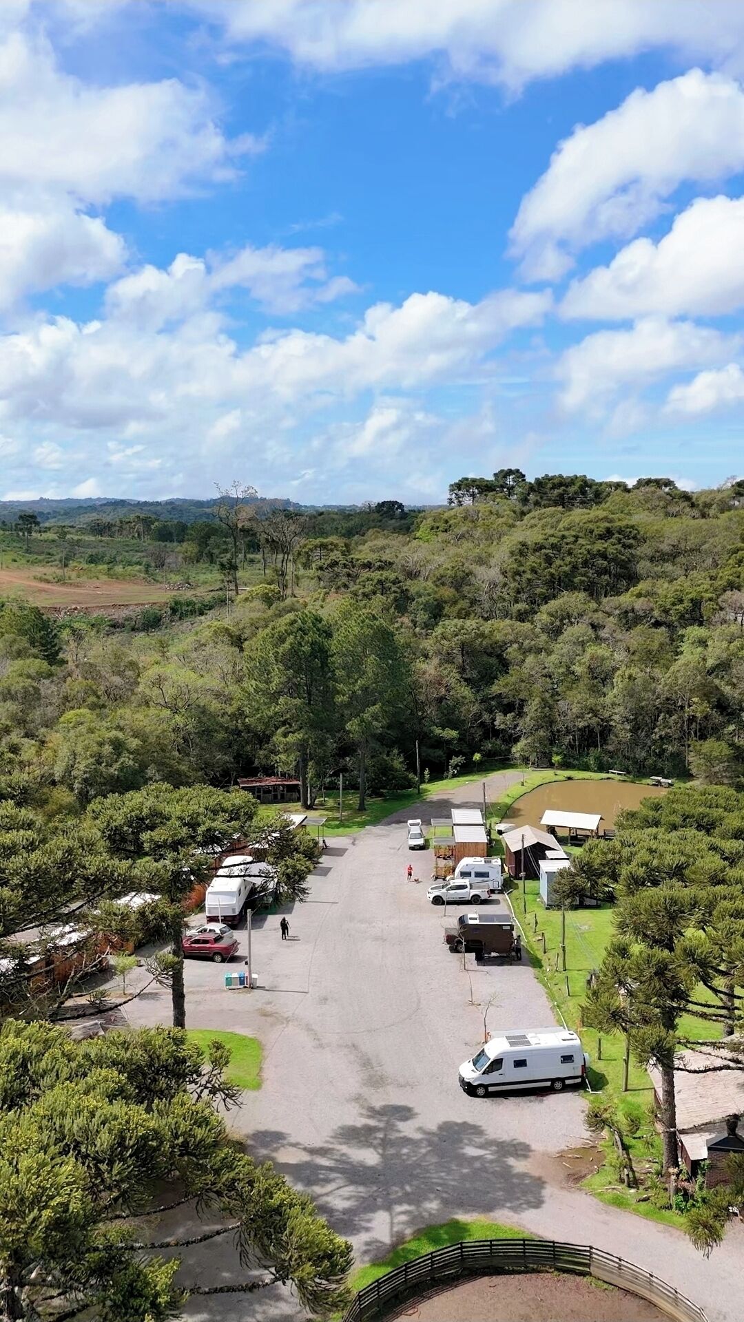 A campground with RVs and tents, surrounded by dense greenery and hills.