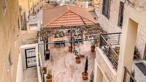 A courtyard with outdoor seating, surrounded by buildings with tiled roofs and balconies.