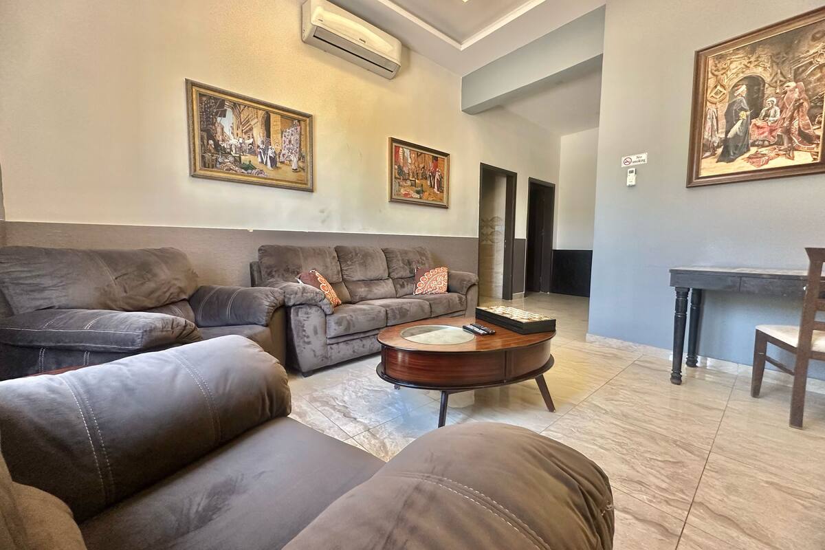 A living room with a sofa, a coffee table, and paintings on the wall.
