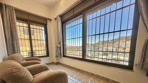 A room with a sofa, large windows with metal bars, and a tiled floor.