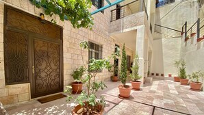 A courtyard with terracotta planters, a decorative metal gate, and a tiled floor.