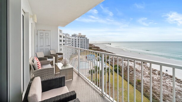 A balcony with wicker furniture, a view of the beach, and a pool area. - Moonspinner by Book That Condo (Panama City Beach)