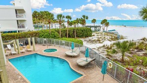 A pool area with lounge chairs and umbrellas, a beach view, and a building with balconies. - Stunning 2 Bedroom Condo with Beach & Pool Access on Siesta Key! (Siesta Key)