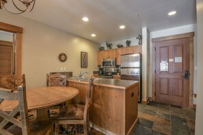 A kitchen with wooden cabinets, a stainless steel refrigerator, and a wooden dining table with chairs.