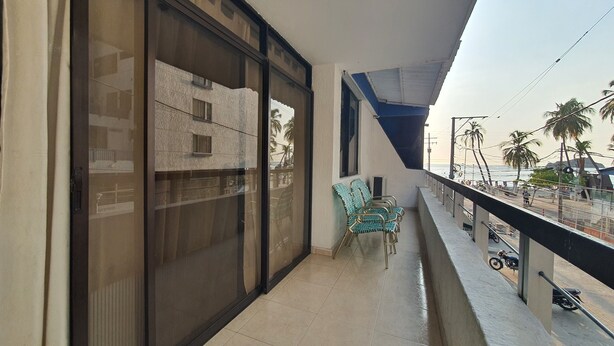 Ein Balkon mit Blick auf ein Gebäude, einem Geländer und einigen Stühlen.