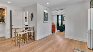 A modern living room with a wooden floor, a white wall, and a green sofa.