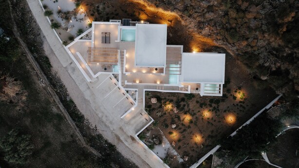 An aerial view of a modern house with a central courtyard, multiple levels, and outdoor lighting. - Pnoes Skyros (Skiros)