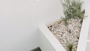 A modern outdoor seating area with wooden chairs and a white wall. - Pnoes Skyros (Skiros)
