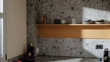 Una cocina con encimeras de granito, armarios de madera y una estantería empotrada con utensilios de cocina.