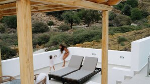 A rooftop terrace with two lounge chairs, a table, and a wooden pergola. - Pnoes Skyros (Skiros)