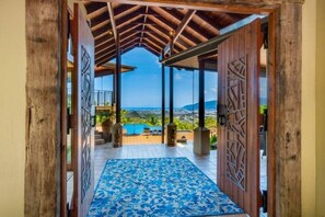 A covered outdoor area with a blue patterned floor, wooden pillars, and a view of the sea and hills. - Barong  luxury private estate with expansive views over Cairns. Unrivalled 
 (Bayview Heights)