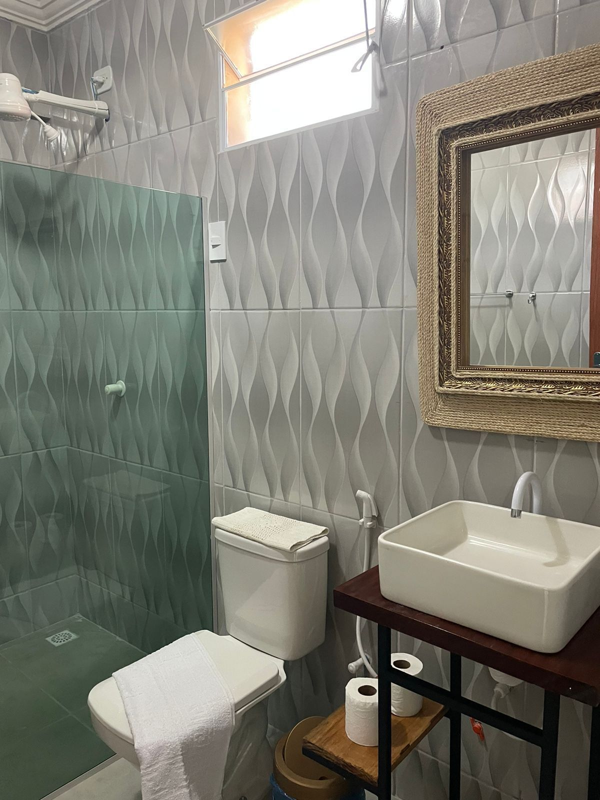 A bathroom with a shower, toilet, sink, and a mirror with a decorative frame.