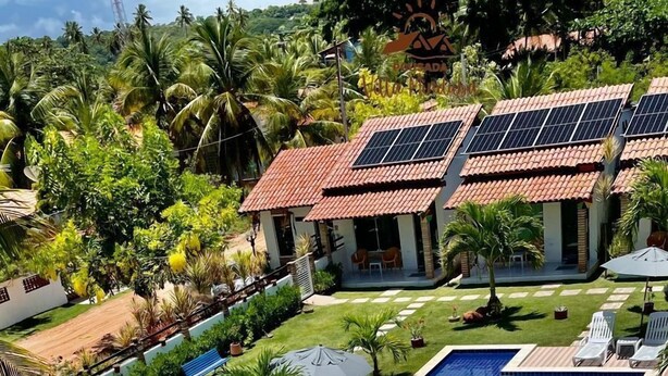 A resort with a long swimming pool, sun loungers, and a covered patio area. - Pousada Villa Minduba (Japaratinga)