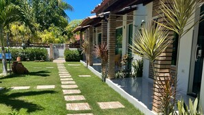 A well-maintained garden with a stone pathway leading to a building with a tiled roof. - Pousada Villa Minduba (Japaratinga)