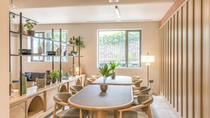 A modern meeting room with a wooden table, chairs, shelves with plants, and a large window. - Niche Living Rathmines (Dublin)