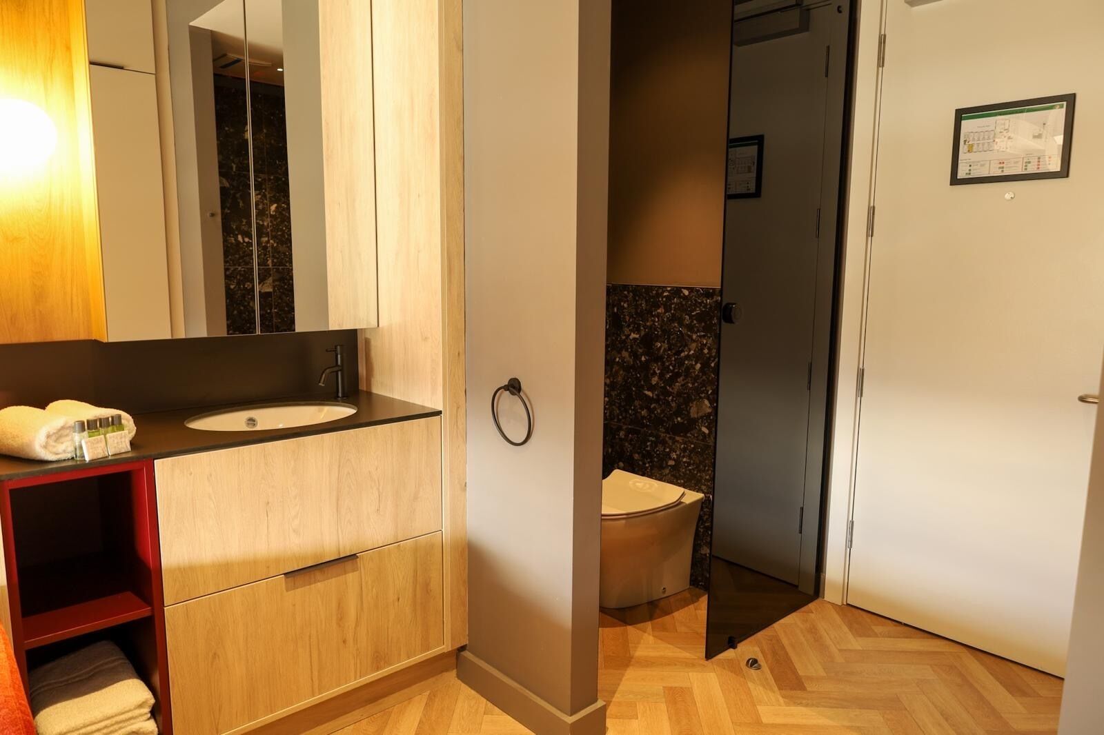 A modern bathroom with a wooden vanity, a sink, and a toilet.