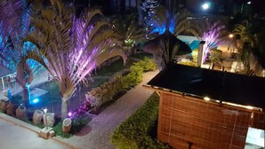 A nighttime view of a landscaped garden with illuminated palm trees and a pathway leading to a building. - Villa Rocher - Residence 2 (Fond du Sac)