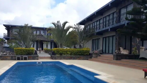 A swimming pool with a modern building in the background. - Villa Rocher - Residence 2 (Fond du Sac)