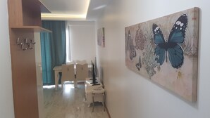 A room with a dining area, a painting of a butterfly, and a wooden cabinet with hooks. - vbasuıten (Istanbul)