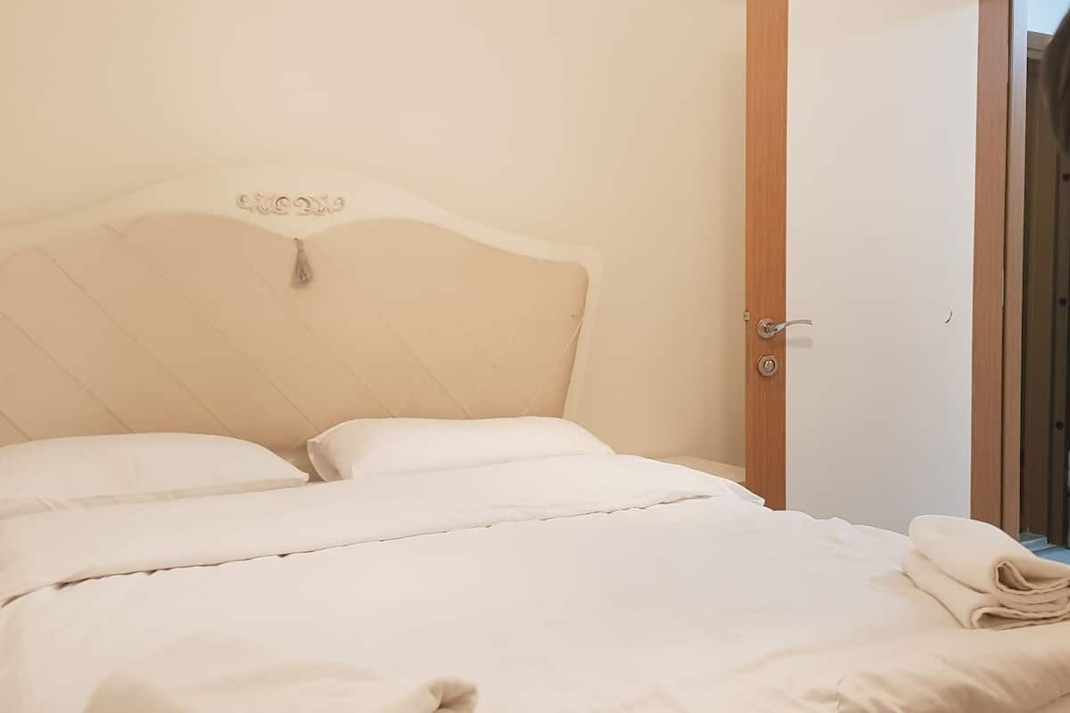 A neatly made bed with a headboard, a wooden door frame, and a small hanging ornament.