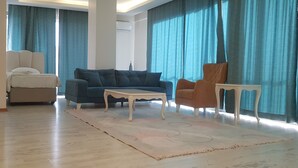 A living room with a beige sofa, a dark blue sofa, a white coffee table, and a brown armchair. - vbasuıten (Istanbul)