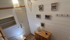 Une chambre avec un lit superposé, une commode en bois et des étagères murales ornées de tableaux encadrés.