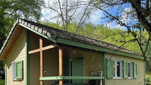Une petite cabane à un seul étage, dotée d’une véranda et d’un coin repas.