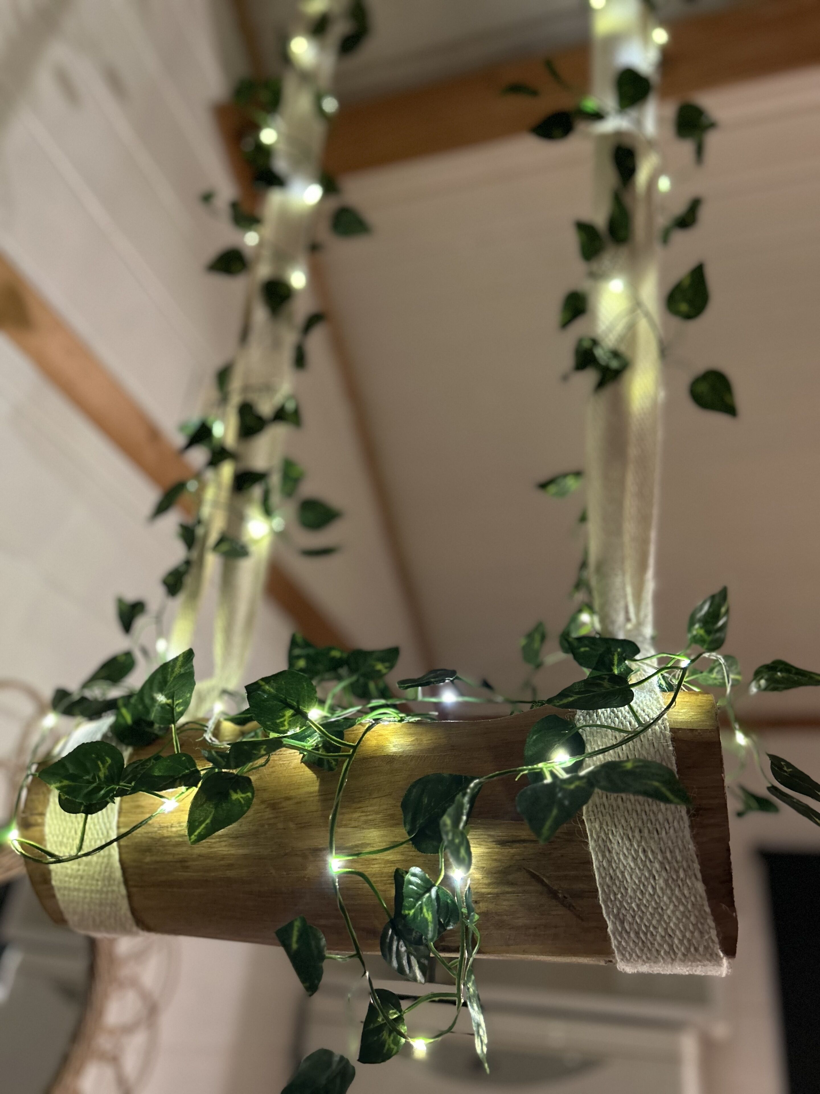Ein Holzbalken mit Efeu und Lichterketten.