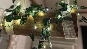 Une poutre en bois ornée de lierre et illuminée de guirlandes lumineuses.