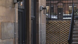 A building with a stone facade, a black door, and a metal fence. - SH Apartments - Dixon Street (Glasgow)