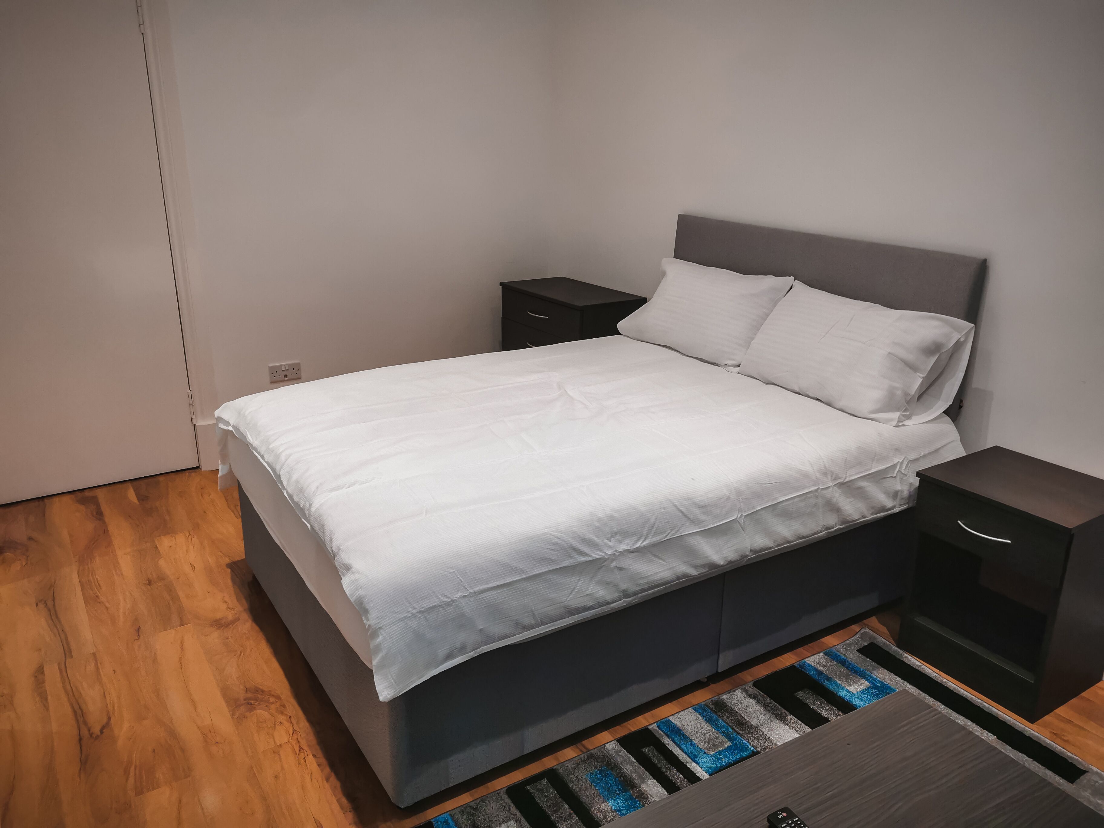 Une chambre à coucher moderne avec un lit, des tables de chevet et un tapis.