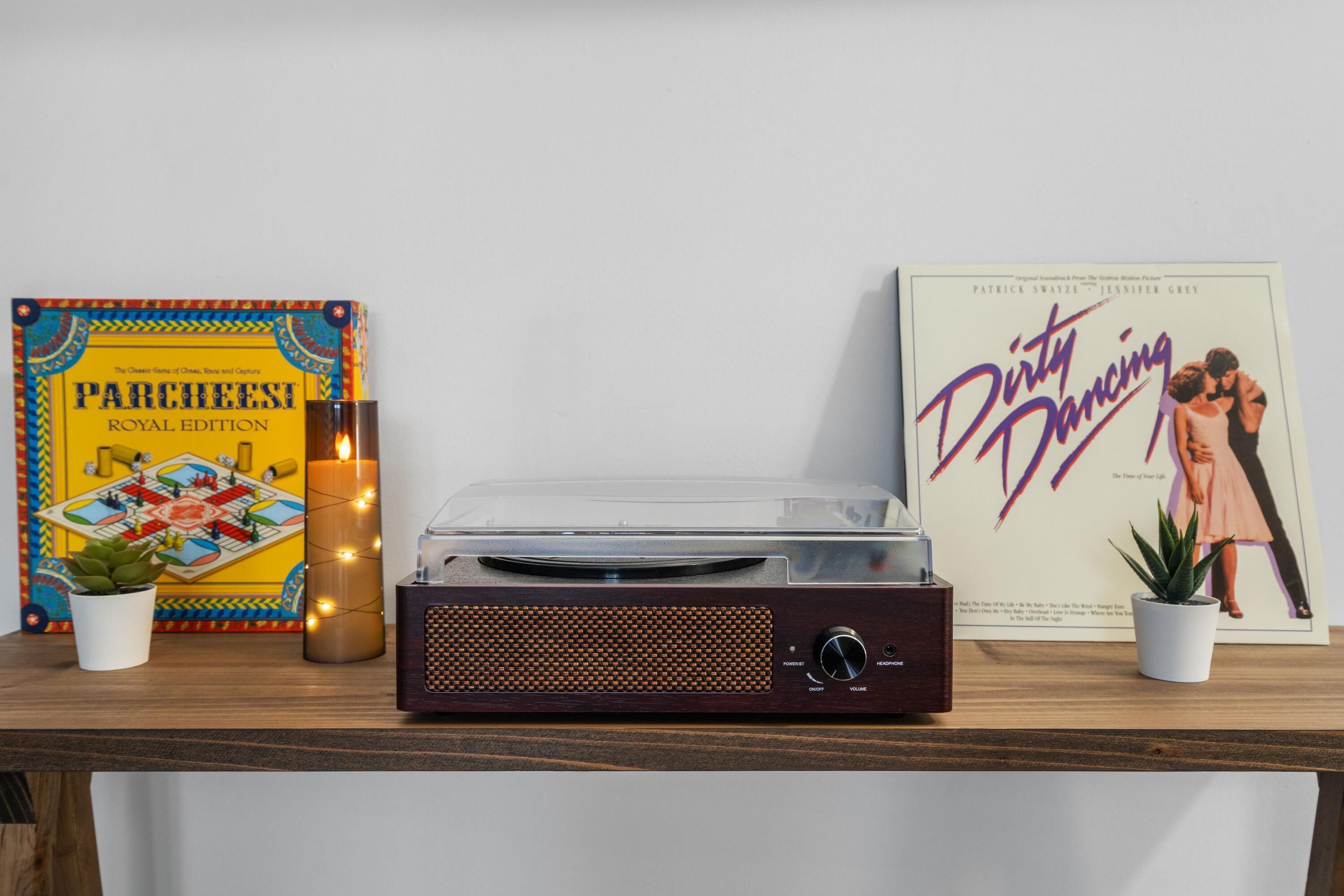 Une platine vinyle, un livre intitulé « Dirty Dancing » et un jeu de société sur une étagère en bois.