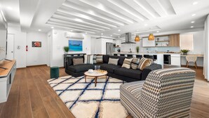 A modern living room with a sectional sofa, a patterned armchair, and a coffee table. - Otium Rentals Vacation Rental at Casa Elena (San Juan)