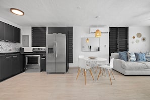 Una cocina moderna con refrigerador, horno y comedor con mesa y sillas.