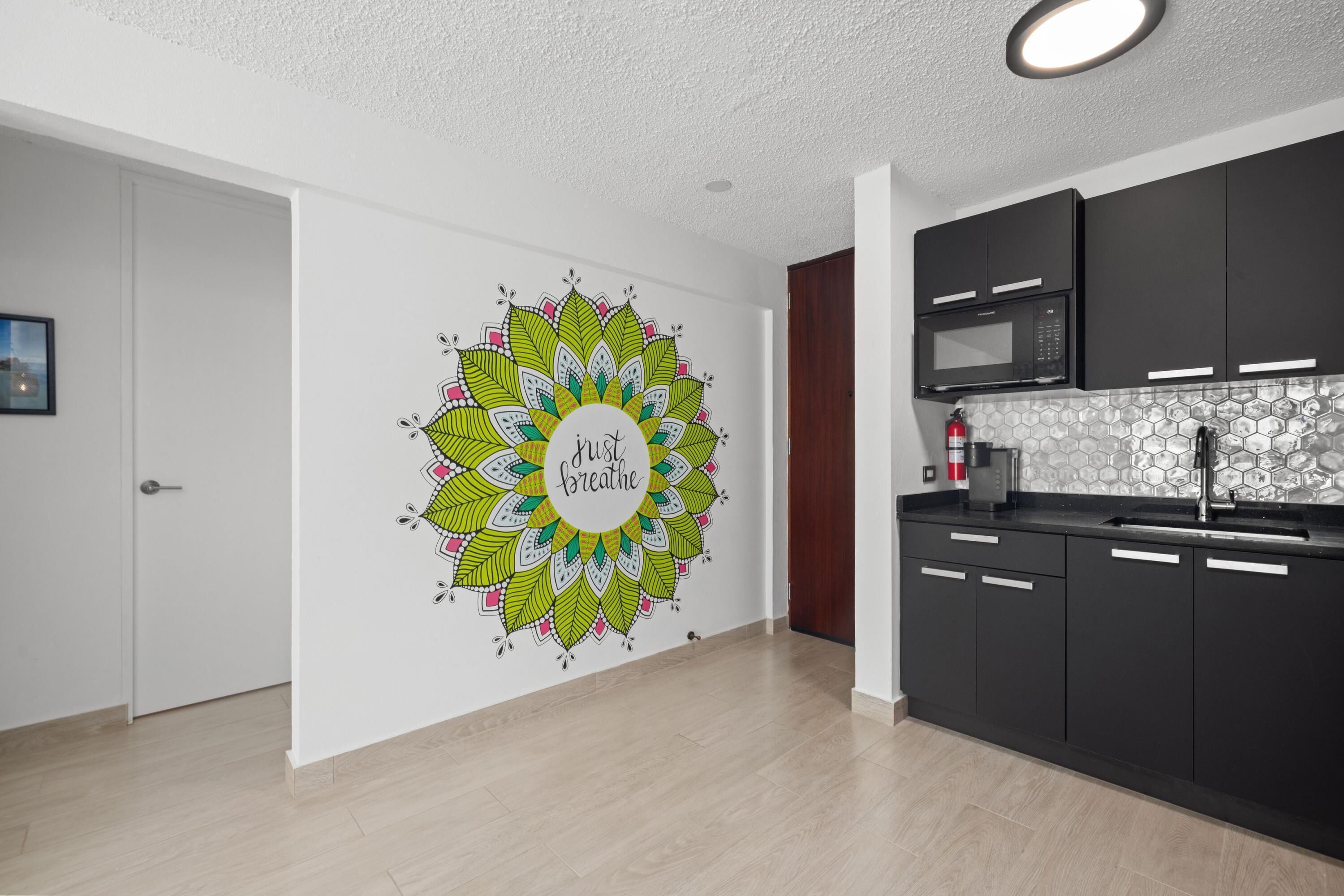A modern kitchen with dark cabinets, a microwave, and a patterned backsplash.