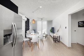 A modern kitchen with a built-in refrigerator, a dining area with a round table and chairs, and a ceiling fan. - Otium Rentals Casa Elena Getaway (San Juan)