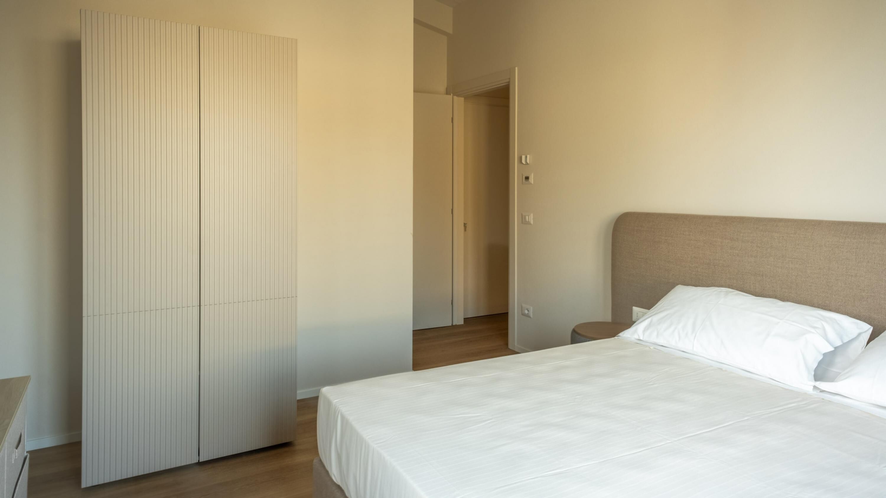 Een slaapkamer met een bed, nachtkastje en garderobe.